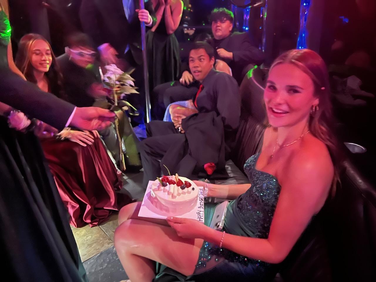 Girl on party bus with her friends holding a birthday cake